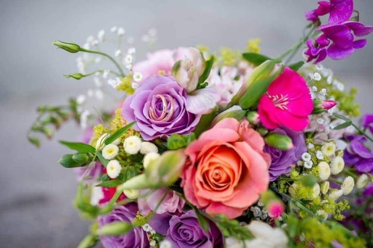 Ein farbenfroher Blumenstrauß mit Rosen, Flieder und kleinen weißen Blüten, perfekt für besondere Anlässe oder als Dekoration.