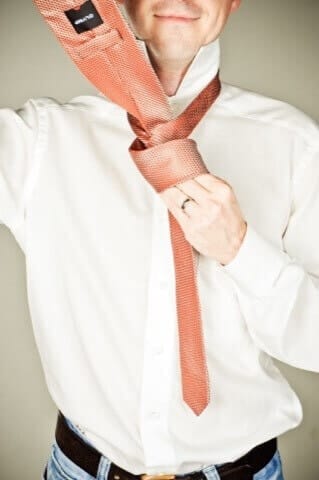 Man adjusting his tie, professional business photography in the Munich photo studio, elegant portrait, fashionable business pictures, high-quality photographs for work and career, Photogenika photo studio Munich.