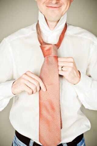 Man putting on a tie in a professional photo studio in Munich, high-quality business portrait, friendly expression, modern atmosphere, ideal for business and application photos.