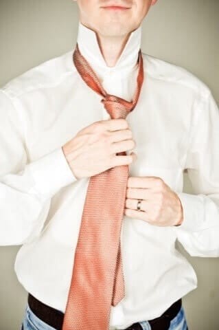 Elegant person tying her tie knot in Munich photo studio, high quality wedding or portrait photography, playing with fashion and style.