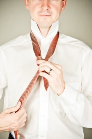 High-quality portrait of a man tying his tie in a Munich photo studio, professional business photography, modern, stylish, authentic, exclusive studio quality, Photogenika Munich.
