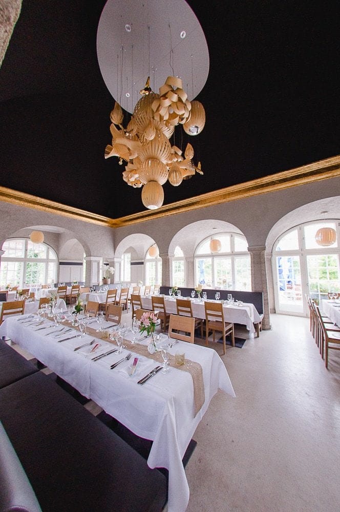 Elegantes Foto von der Festlocation bei Photogenika Fotostudio in München, mit stilvollem Kronleuchter und festlich gedeckten Tischen, perfekt für Hochzeiten, Events und Feiern.