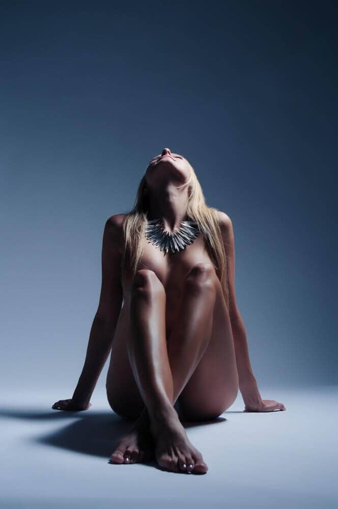 Portrait of a naked woman in a studio with shimmering jewelry, artistically charged nude photography in Munich.