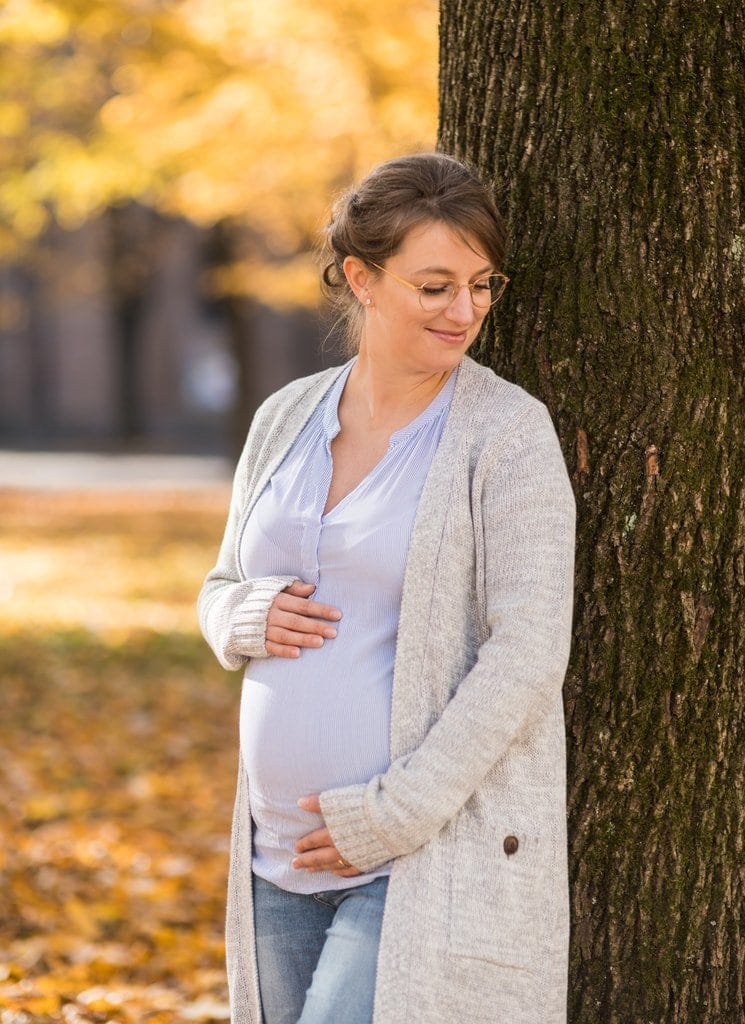 Naturfotografie mit schwangere Frau im Herbst, bei Photogenika Fotostudio München, professionelles Babybauch-Fotoshooting, herzliche Portraits vor Herbstkulisse.
