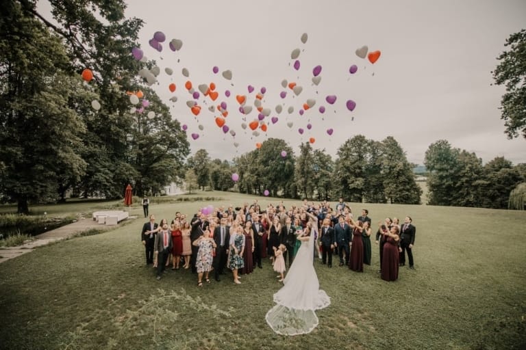 Fröhliche Hochzeitsgesellschaft beim Fotoshooting im Münchner Park, mit Luftballons und romantischer Atmosphäre. Professionelles Fotostudio für Hochzeitsfotografie in München.