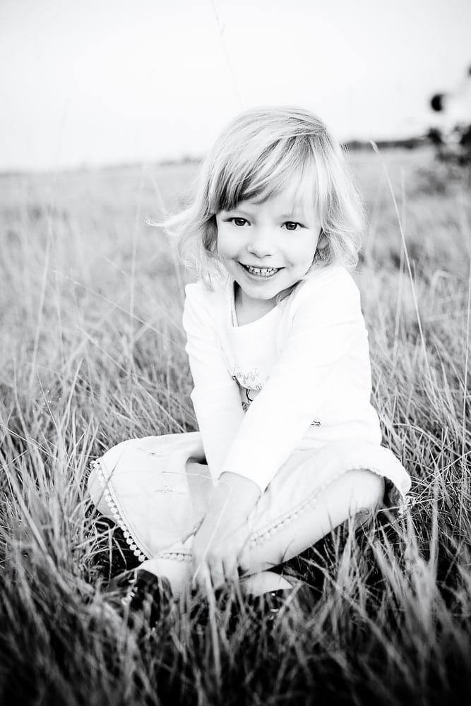 Schwarzweiß kindliches porträt, kindergesicht mit lachendem gesicht, kind in natur, Fotostudio München, Kinderfotografie München.