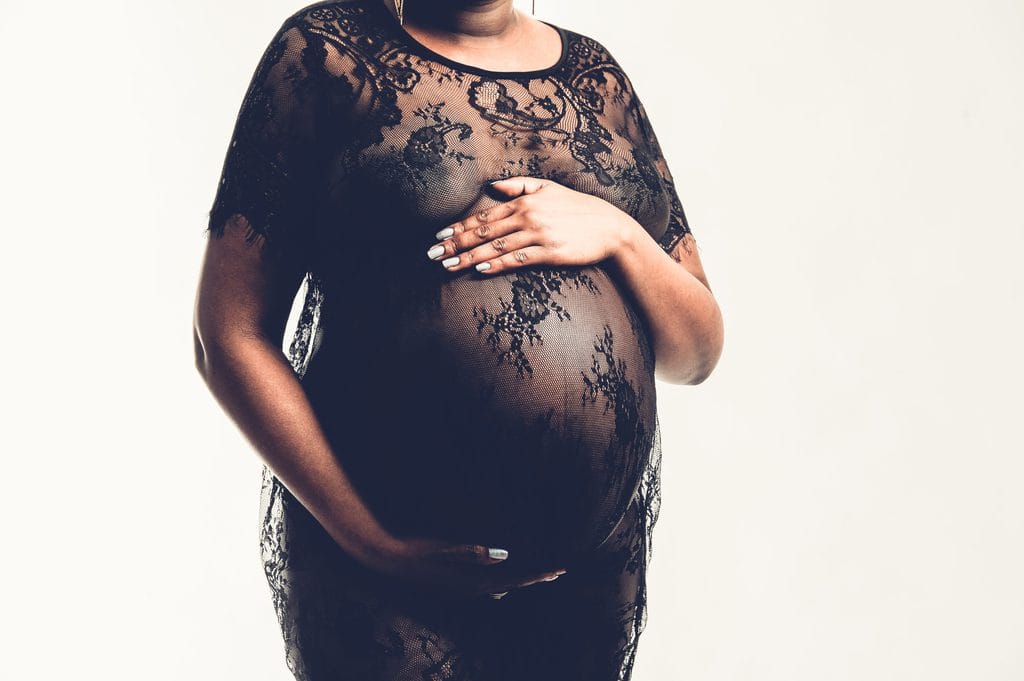 Stilisiertes Schwangerschaftsbild in einem schwarzen Spitzenkleid, professionelle Schwangerschaftsfotografie in München.