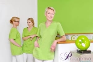 Drei Pflegekräfte in grünen Uniformen im Gespräch in einem medizinischen Umfeld, freundliche Atmosphäre, professionelle Pflegekräfte.