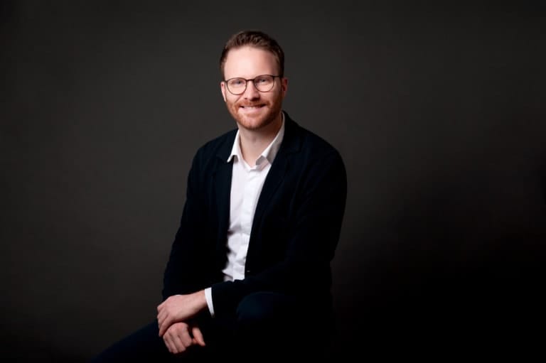 Herr im Business-Look vor dunklem Hintergrund, professionelles Fotoshooting für Profilbilder.