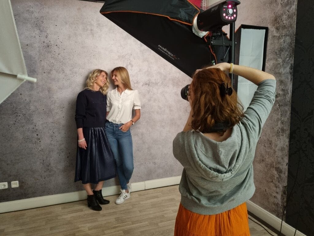 Leuchtende Szene mit zwei lachenden Frauen beim Fotoshooting in modernem Studio