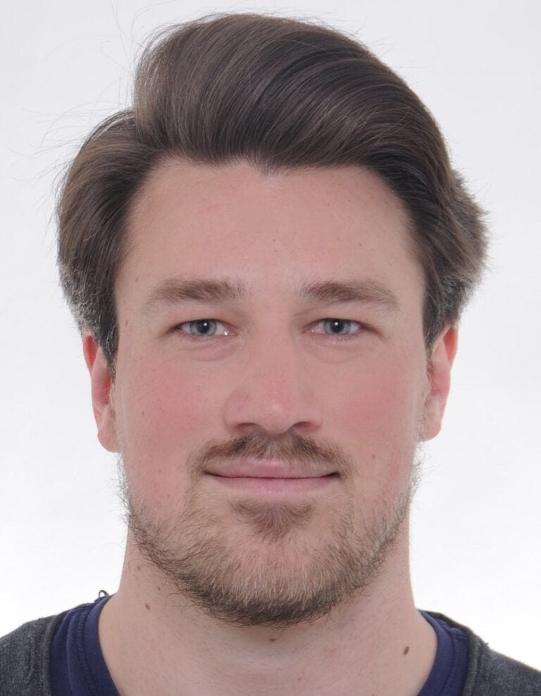 Passport photo of a young man with dark hair against a white background