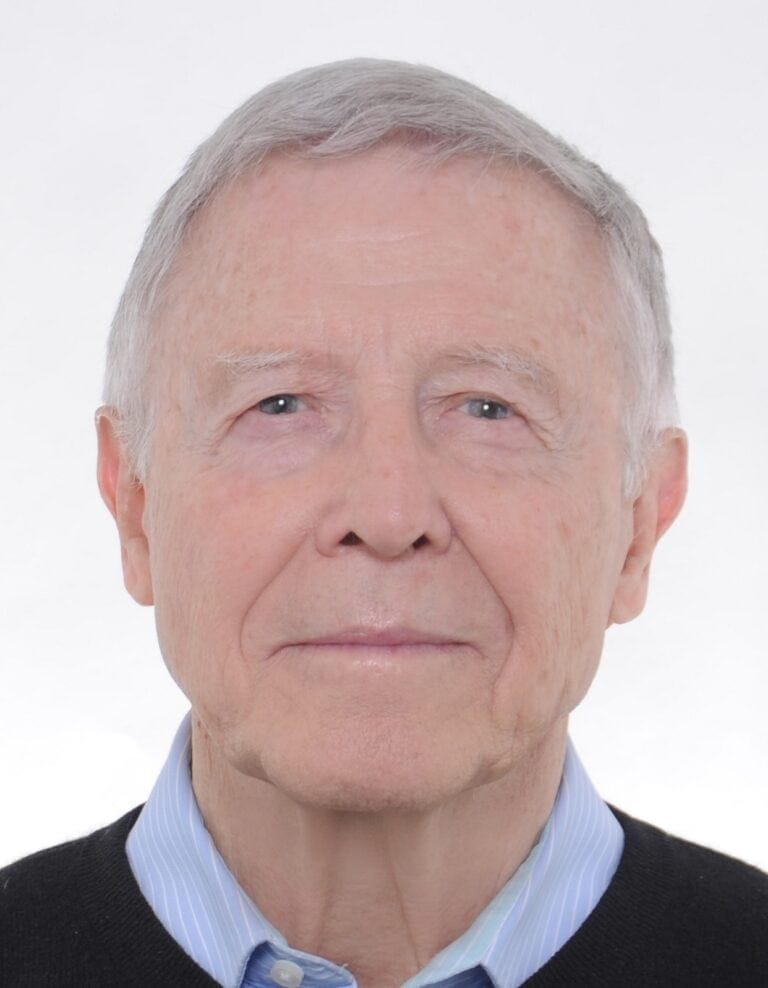 Nahaufnahme eines älteren Mannes mit grauen Haaren und blauen Augen, formelles Outfit, professionelles Passfoto.