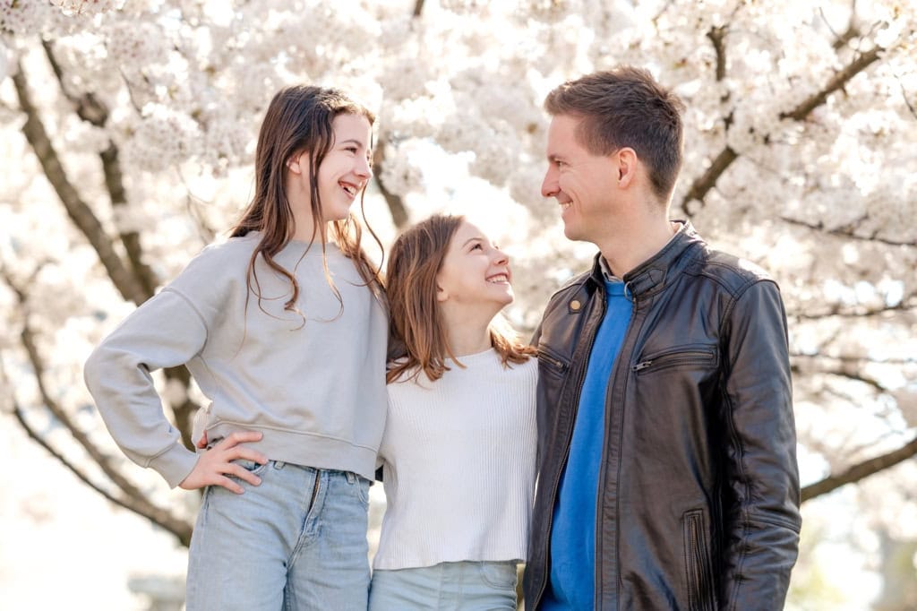 A family posing for a photo under a cherry tree.