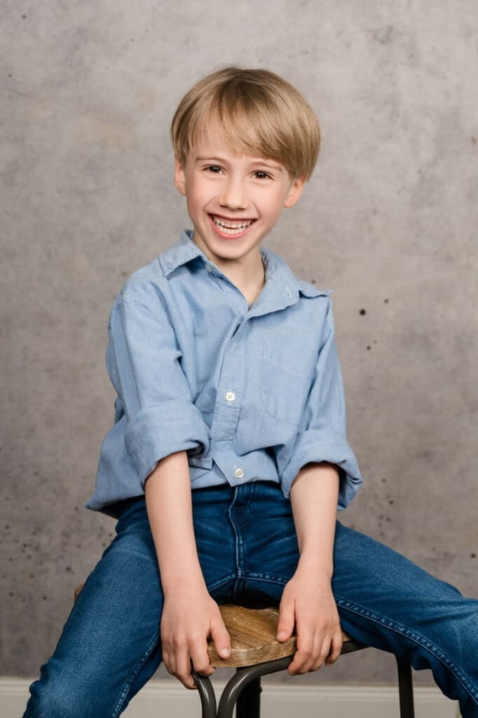 Fröhliches Kinderportrait eines lachenden Jungen im Fotostudio.
