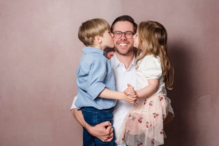 Emotionaler Familienmoment: Kinder geben ihrem Vater einen Kuss.