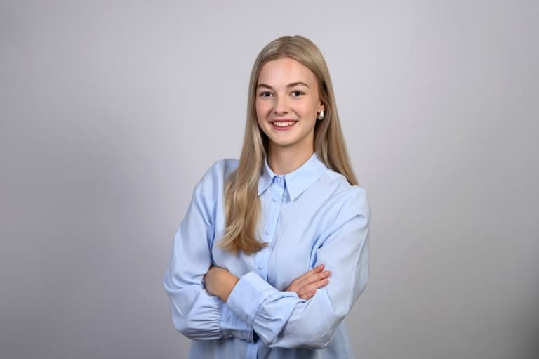 Sympathische Bewerberin mit blonden Haaren und verschränkten Armen.