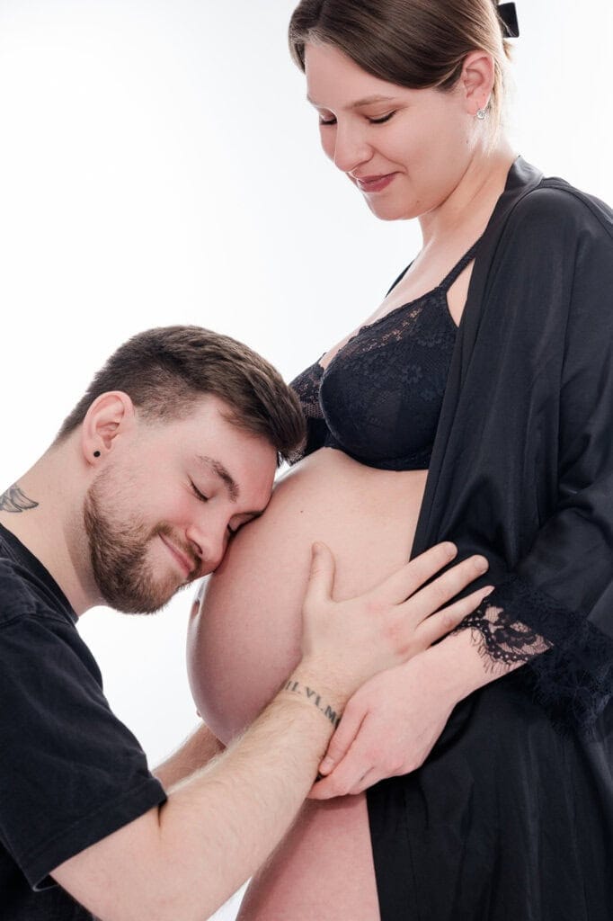 Partner küsst zärtlich den Babybauch der Schwangeren