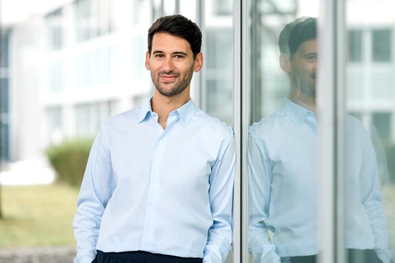 Business-Porträt eines Mannes im blauen Hemd am Fenster lehnend.