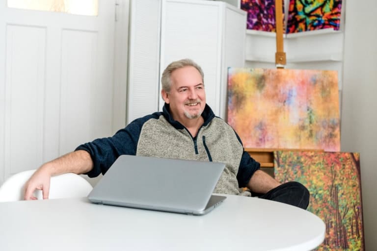 1. Hochwertiges Portraitfoto eines lachenden Mannes vor einer Kunstwand in einem Fotostudio in München.