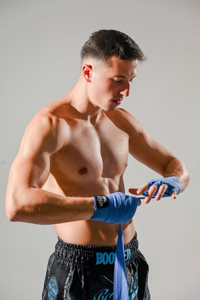 Kraftsportler beim Anlegen des Boxbands, professionelles People-Foto in einem Studio in München, geeignet für Sport-, Fitness- oder Kampfsportmarketing.