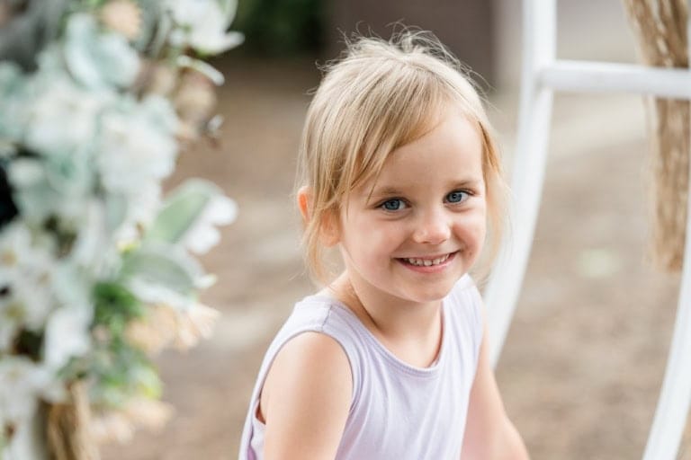 Nahaufnahme eines lächelnden blonden Mädchens im Garten.