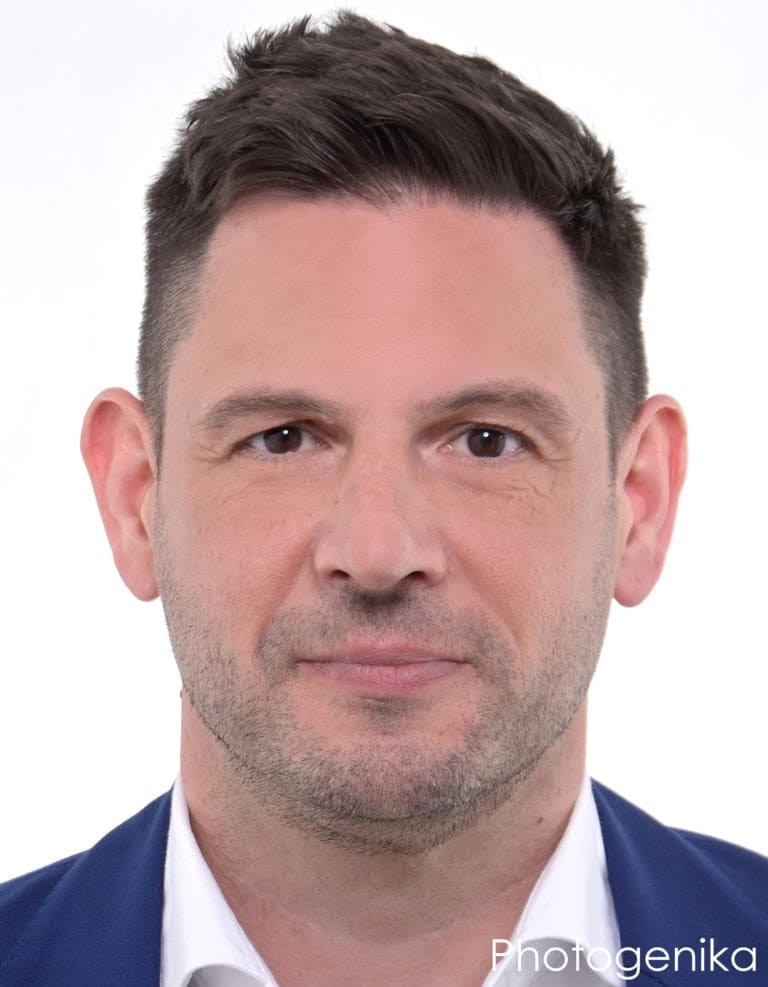 Biometrisches Passfoto eines Mannes im blauen Sakko und weißen Hemd.